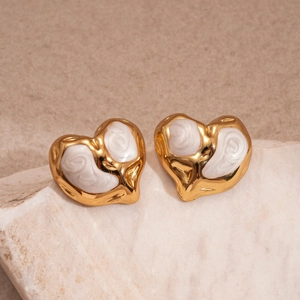 Macro detail of gold-plated heart earrings with white marble enamel on stone base