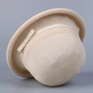 Detail of beige knitted bucket hat featuring fine texture and a delicate ribbon bow