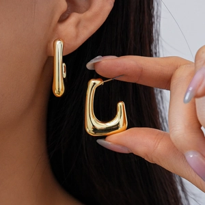 Close-up of a model wearing minimalist golden U-shaped earrings with a smooth metal finish