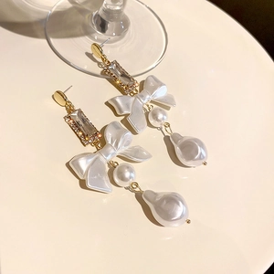 Detail of elegant bow earrings with pearls and rhinestones on a white tray