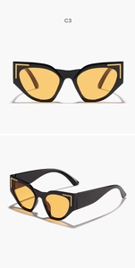 Close-up of cat-eye sunglasses with wide black frame, orange lenses and gold metal details