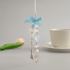 Detail of blue ribbon bow phone strap with silver guitar charm and pearl beads
