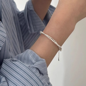 Silver beaded bracelet with pearls and adjustable chain worn on a model wrist