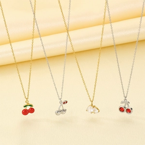Detailed close-up of four cherry pendant necklaces in enamel and zircon finishes