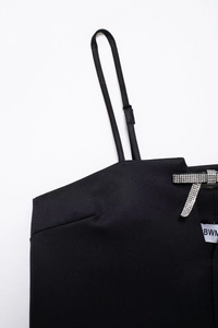 Detalle de un vestido negro de tirantes con lazo de pedrería y tiras finas