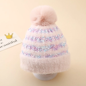 Gros plan détaillé d'un bonnet en tricot rose avec des rayures colorées et un pompon moelleux