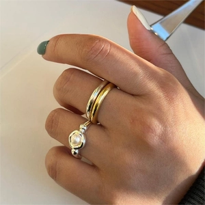 Detail of minimalist gold and silver ring set with pearls worn on model's fingers