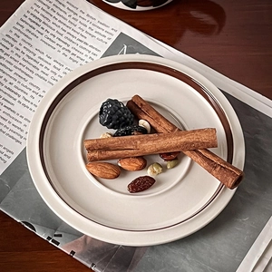 Top view of vintage hand-painted ceramic saucer with brown rim and cinnamon sticks