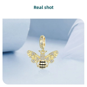 Macro detail of a 14k gold-plated bee charm with pavé crystals and black enamel stripes
