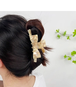 Elegant marble pattern acetate bow hair claw clip styled on dark long hair back view