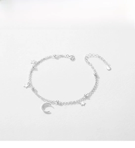 Detail of silver double-layered bracelet featuring star charms and a CZ moon pendant