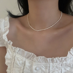Close-up of delicate 2-3mm freshwater pearl necklace on model with lace top
