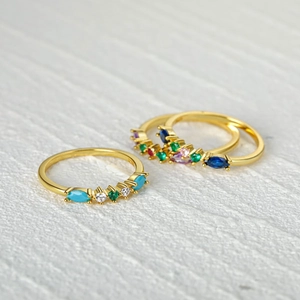 Macro detail of three slender gold rings set with colorful marquise gemstones