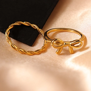 Elegant gold-tone bow and twisted rope stackable ring set on silk background