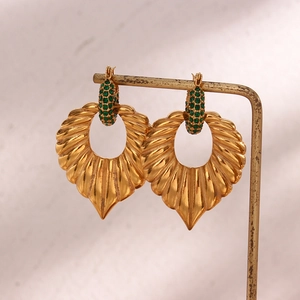 Detail of vintage leaf pendant earrings with green cubic zirconia in 18K gold plating