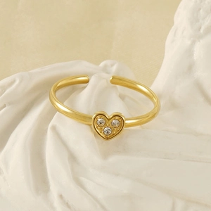 Close-up of heart-shaped gold ring with three clear zircons on artistic plaster prop