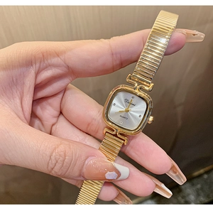 Macro view of a square gold quartz watch with diamond markers and elastic metal strap