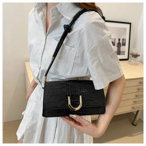 Détail du sac bandoulière noir motif crocodile avec boucle dorée en U et bandoulière nouée