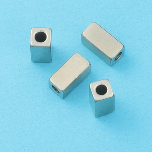 Macro detail of four silver square metal spacer beads for DIY jewelry on blue background