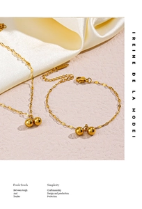 Macro view of gold plated bead charms on stainless steel necklace and bracelet set