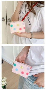 Close-up of pink polka dot PU leather wallet with gold hardware zipper and brand plate