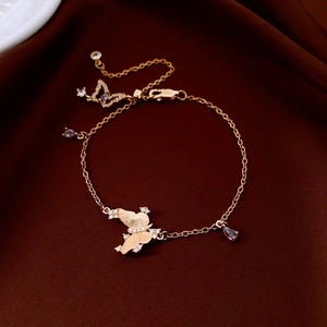 Detail of gold butterfly bracelet with zircon inlay and teardrop charms on velvet