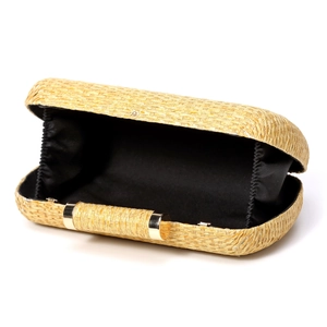 Detail view of woven straw clutch showing black fabric lining and gold metal clasp