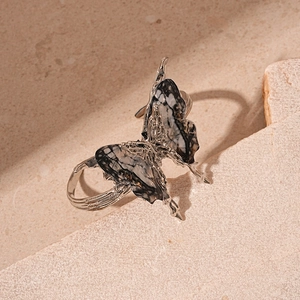 Close-up of vintage butterfly ring with marble resin wings on textured stone surface