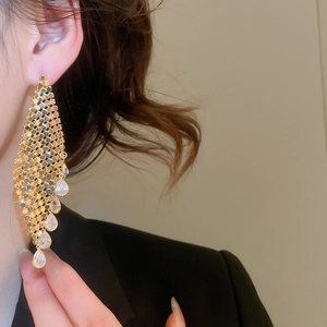 Detail of gold-plated mesh earrings with shimmering teardrop tassels on a model