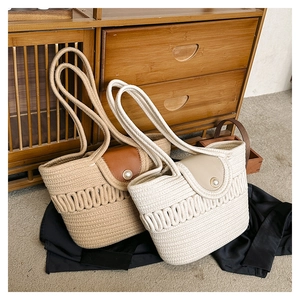 Detail of woven tote bags with pearl buckle and long straps in khaki and off-white