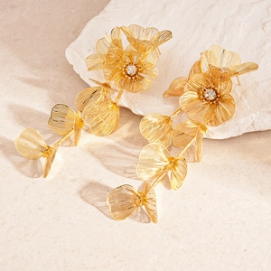 Detail of golden mesh flower drop earrings with crystal centers on stone base