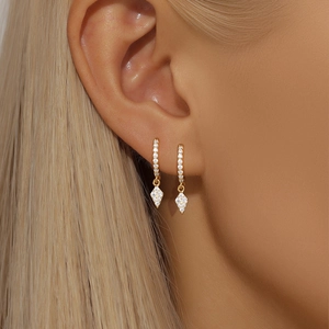 Close-up of golden S925 silver earrings featuring a diamond-studded rhombus pendant charm
