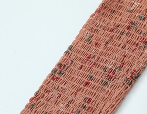 Gros plan sur la texture du tissu fleuri smocké avec détails élastiques sur haut brique