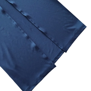 Detail view of smooth dark blue skirt fabric showing split hem and double stitching