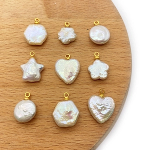 Macro view of baroque pearl pendants in heart and star shapes on a wooden base
