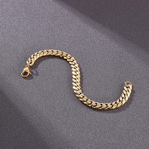 Detail of a gold-plated Cuban link bracelet with a secure lobster clasp on grey texture
