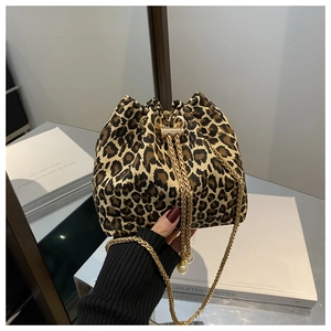 Primer plano de un bolso de mano con estampado de leopardo y cadena dorada con perlas.