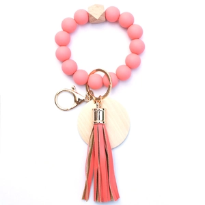 Detail of pink silicone beads, wooden accents, and leather tassel on the bracelet keychain