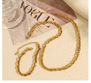 Detailed view of polished gold flat Cuban chain necklace and bracelet set on a magazine