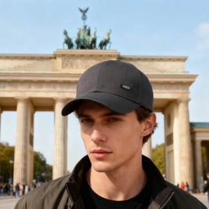 Men's dark grey baseball cap with metal sport badge in front of Brandenburg Gate