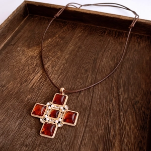 Macro shot of vintage cross pendant with amber resin stones and pearls on wood