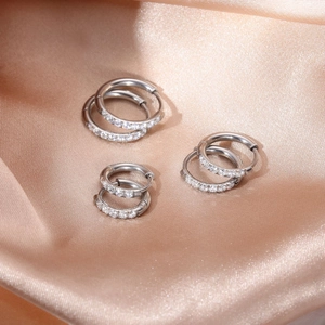Close-up of silver-plated hoop earrings set with sparkling zircon on silk background