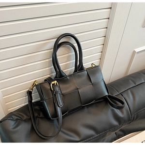 Dettaglio della trama in pelle intrecciata nera della borsa con finiture in metallo oro