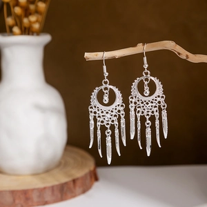 Ethnic silver-style peacock bell tassel earrings with hollow leaf design on wood branch