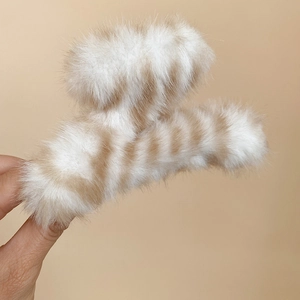 Détail de la pince à cheveux rayée en peluche avec texture douce en fausse fourrure beige