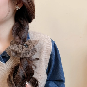 Detailed close-up of brown knitted scrunchie with fashion label on hair tie