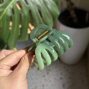 Macro detail of sage green pumpkin-shaped hair claw clip with metallic spring
