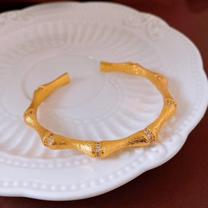 Détail du bracelet en forme de bambou en or mat avec accents de cristaux brillants