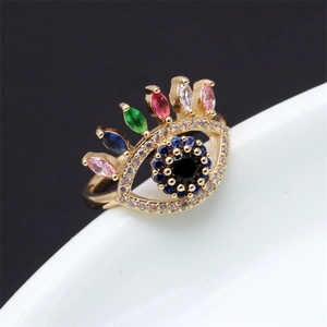 Détail d'une bague en forme d'œil avec zircons colorés et placage à l'or sur fond noir