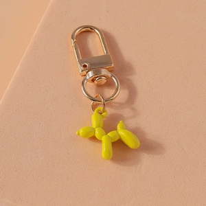 Detailed view of a cute yellow resin balloon dog keychain with golden lobster clasp hardware